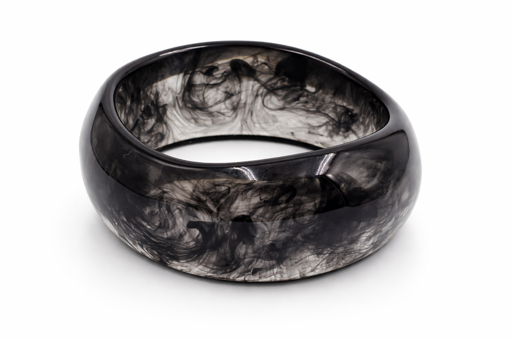 Pulsera rígida ancha de resina efecto mármol negro y gris humo, sobre fondo blanco